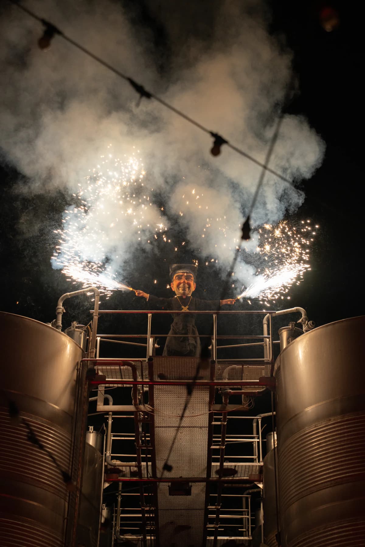 A giant with sparklers above the winery tanks
